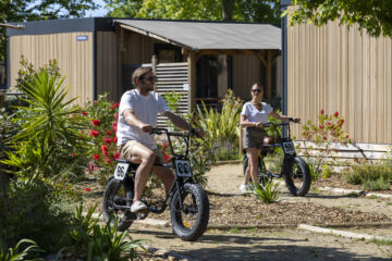 Two tourists on rented e-bikes in a Biscarrosse camping.
